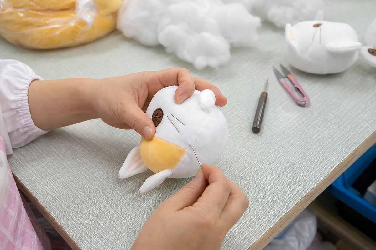 Hand finishing the opening of a custom plush before final QC