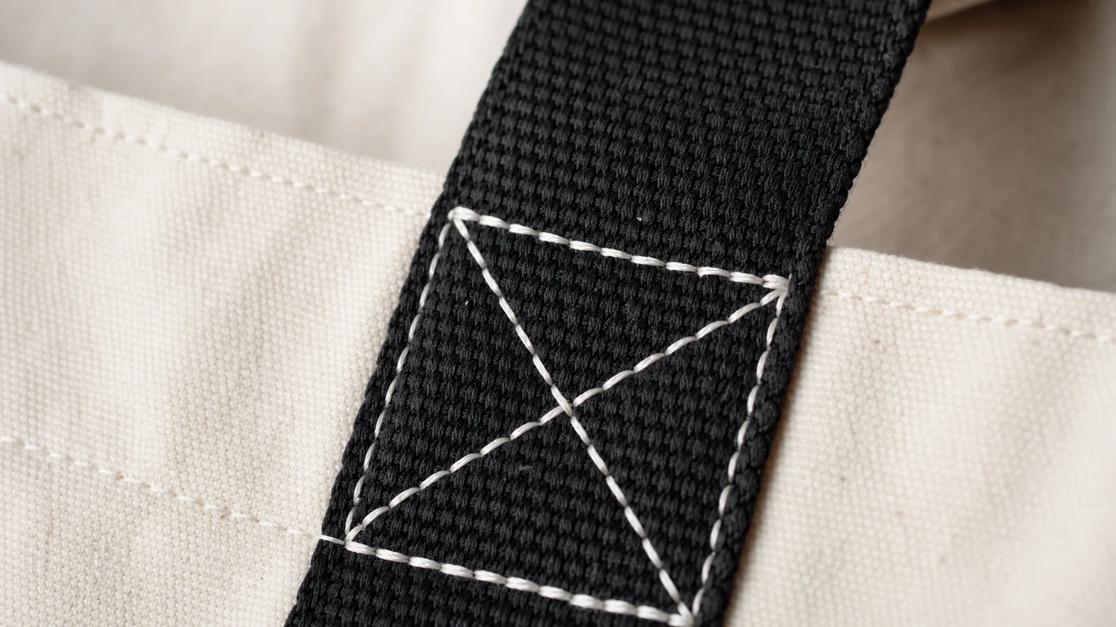Large Event Tote Handle Reinforcement and Box Stitching Close-up of reinforced box stitching where a black webbing handle meets a large canvas tote bag