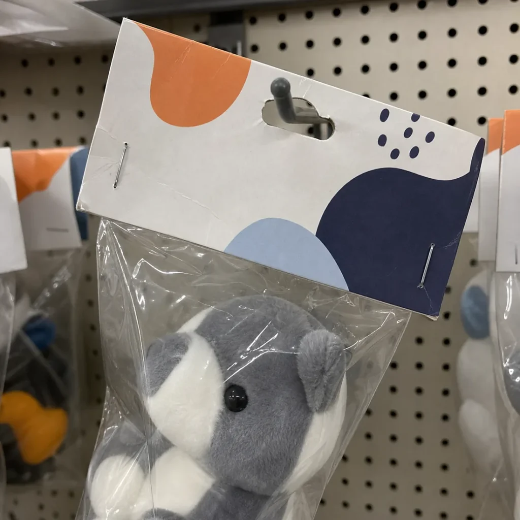 crooked paper header card makes a packaged custom plush hang at an angle on a retail hook