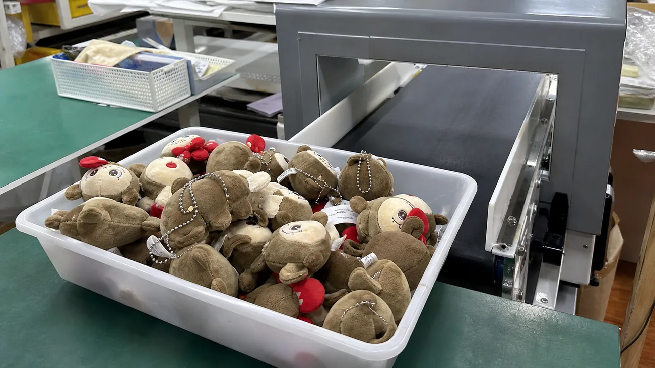 unorganized tray mixing plush toys with metal chains before needle detector inspection