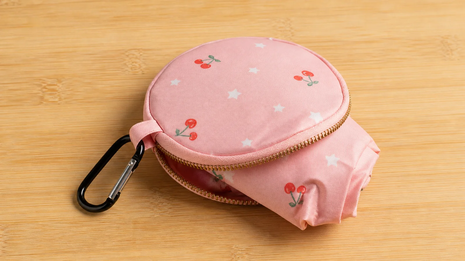 Pink round storage pouch with a carabiner and matching foldable shopping bag fabric visible inside