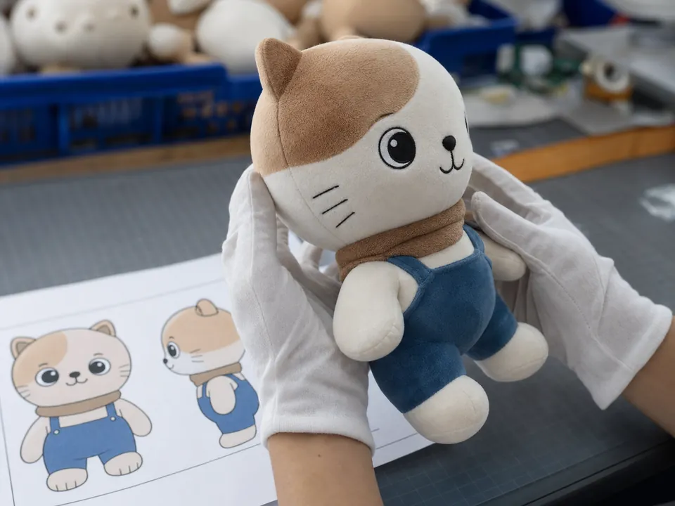 ぬいぐるみ表情と刺繍位置の多角度確認 白手袋でぬいぐるみを45度に回し頬曲線と目位置を仕様図と照合