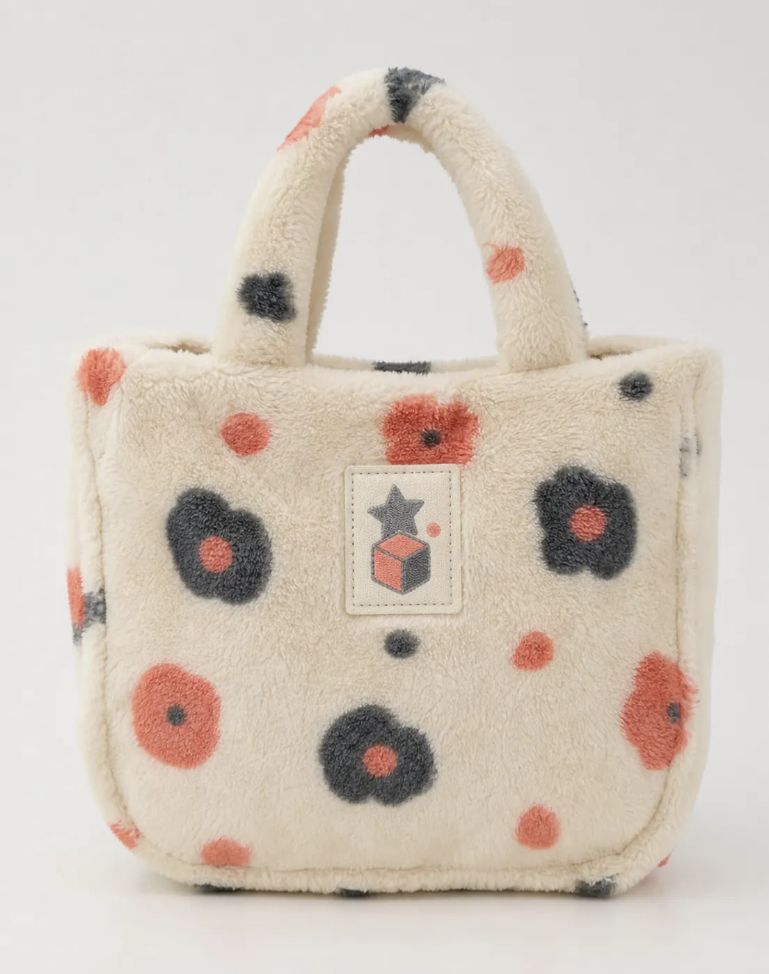 Plush tote bag with short padded handle, all-over pattern, and woven label