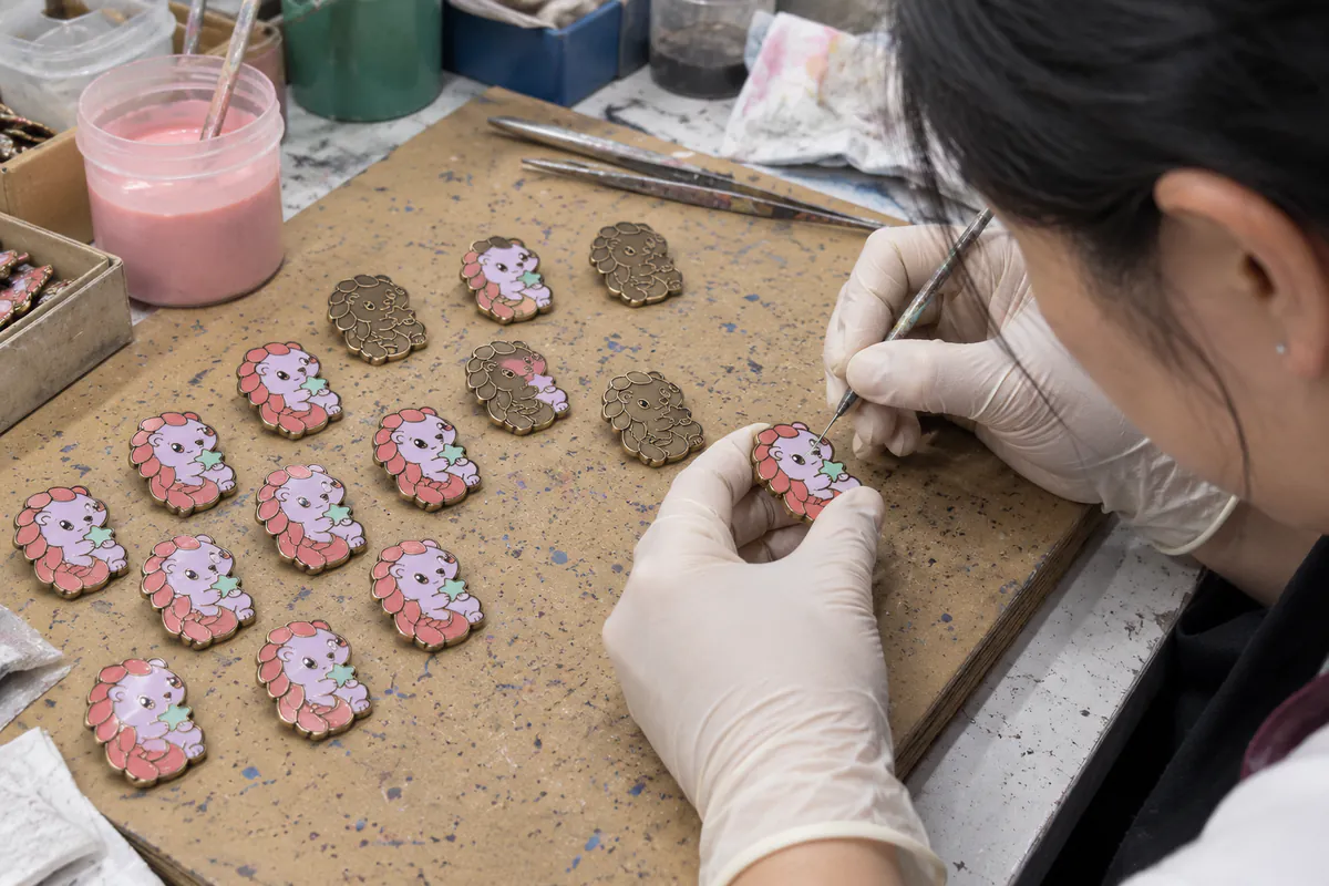 Color being filled into recessed closed cells of a small Moonberry Pangolin pin